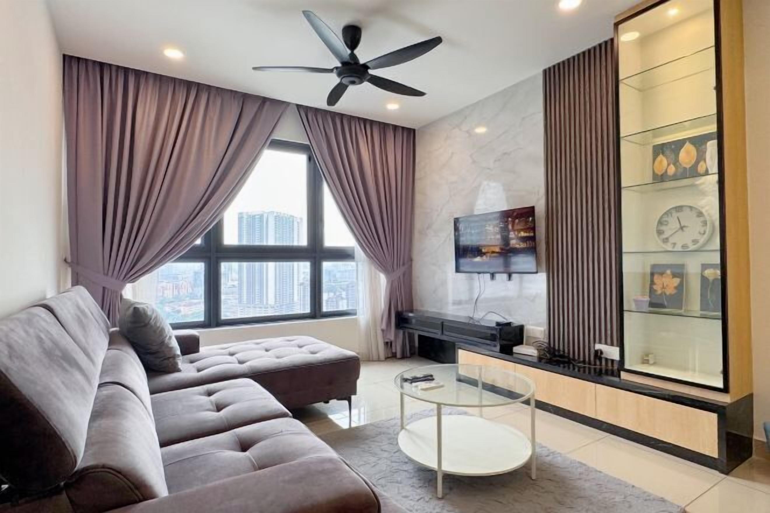 A modern living room with a sofa, a glass coffee table, a TV, and a decorative glass cabinet.