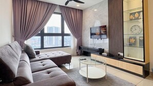 A modern living room with a sofa, a glass coffee table, a TV, and a decorative glass cabinet.