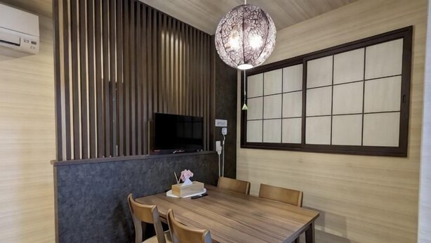 A dining area with a wooden table, chairs, a television, and a decorative light fixture. - Moonlight Inn Kujo (Kyoto)