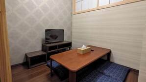 A small room with a wooden table, a television, and a futon bed. - Moonlight Inn Kujo (Kyoto)
