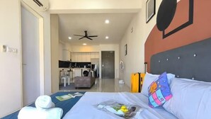 Une chambre d’hôtel avec un lit, un oreiller, une serviette pliée, un magazine et une vue sur la cuisine.