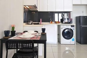 Eine kompakte Küche mit Waschmaschine, Kühlschrank und Essbereich mit Stühlen und Tisch.