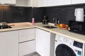 Eine kleine Küche mit Waschmaschine, Kaffeemaschine und Mikrowelle.