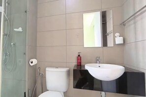 Un baño moderno con inodoro, lavamanos y ducha.