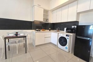 Eine kompakte Küche mit Waschmaschine, Kühlschrank und einer Essecke mit Stühlen.