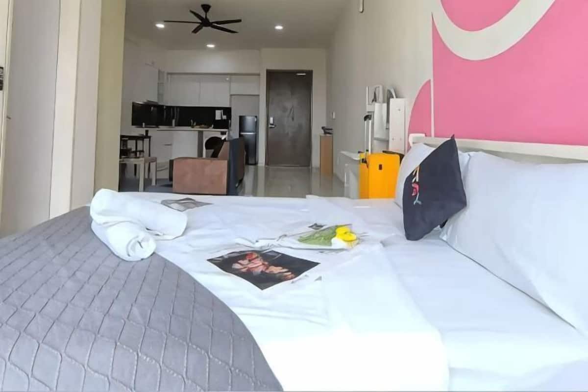 Ein Hotelzimmer mit Bett, Kissen, Decke, Handtuch, Bild, Kopfkissenbezug, Nachttisch, Lampe und Wand mit kreisförmigem Muster.