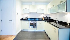 A modern kitchen with white cabinets, a black countertop, and a stainless steel oven. - Thesqua.re Saffron Hill Apartments (London)