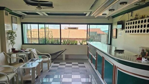 A reception area with a checkered floor, a reception desk, and a view of buildings outside. - Green Mellow Court Capitol Avenue (Dipolog)