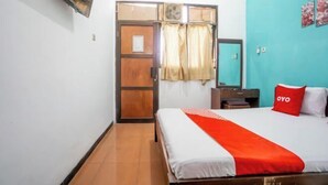 Camera d'albergo con un letto, una TV a muro, una porta con tende e un quadro appeso al muro.