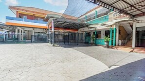 Un'ampia area esterna con un'area salotto coperta, un ingresso recintato e un edificio con una facciata colorata.