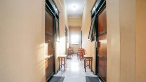Un corridoio con porte in legno, pavimento piastrellato e diversi tavoli e sedie in legno disposti per mangiare.
