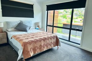 A bedroom with a bed, nightstands, a window with a view, and a ceiling fan. - Lipscombe Mt Wellington view luxury house (Sandy Bay)