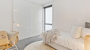Une chambre à coucher moderne avec un lit, une petite table et une chaise.