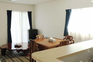 A room with a wooden dining table, two chairs, a small side table, a television, and a window with curtains. - DanXiaGE in country near the sea (Itoman)