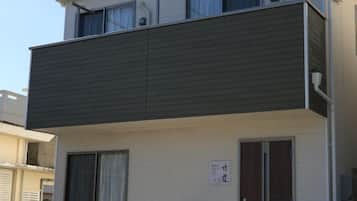 Um edifício de dois andares com uma varanda escura e uma placa indicando espaço para negócios ou escritório.