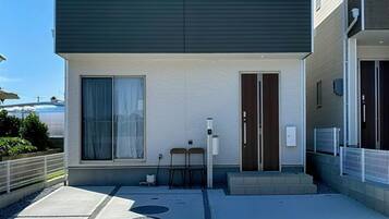 Um edifício moderno com teto plano, uma porta e uma pequena área externa com mesa e cadeiras.
