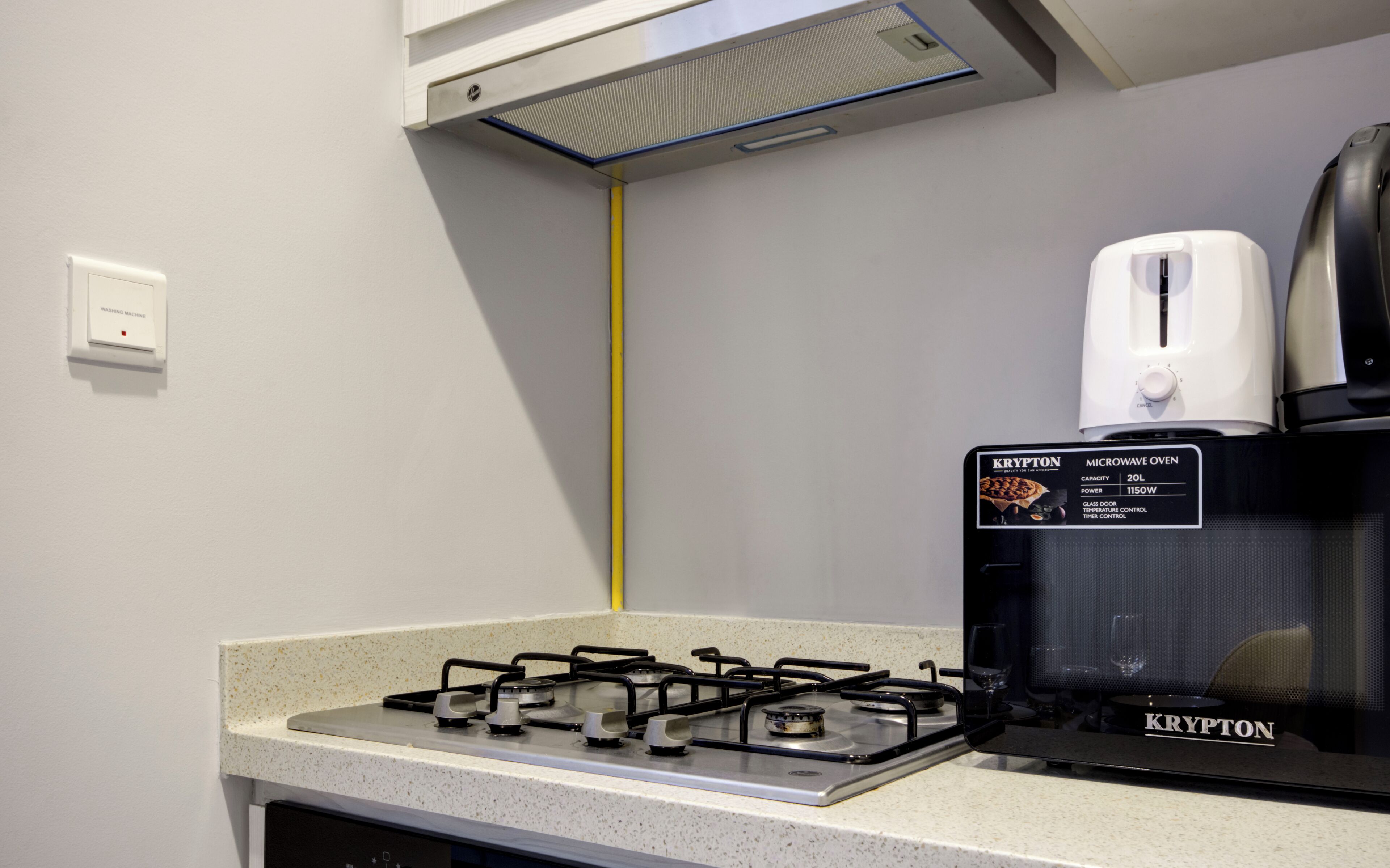 Una cocina equipada con estufa a gas, microondas y tostadora.