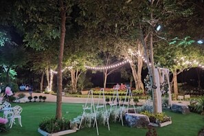 An outdoor garden area with a pergola, string lights, and seating arrangements. - Keith Ratchaburi (Ban Pong)