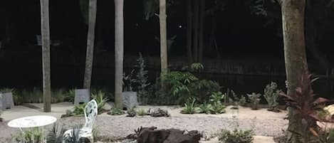 Un espacio al aire libre con una mesa y sillas, rodeado de árboles y plantas.