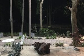 An outdoor area with a table and chairs, surrounded by trees and plants. - Keith Ratchaburi (Ban Pong)