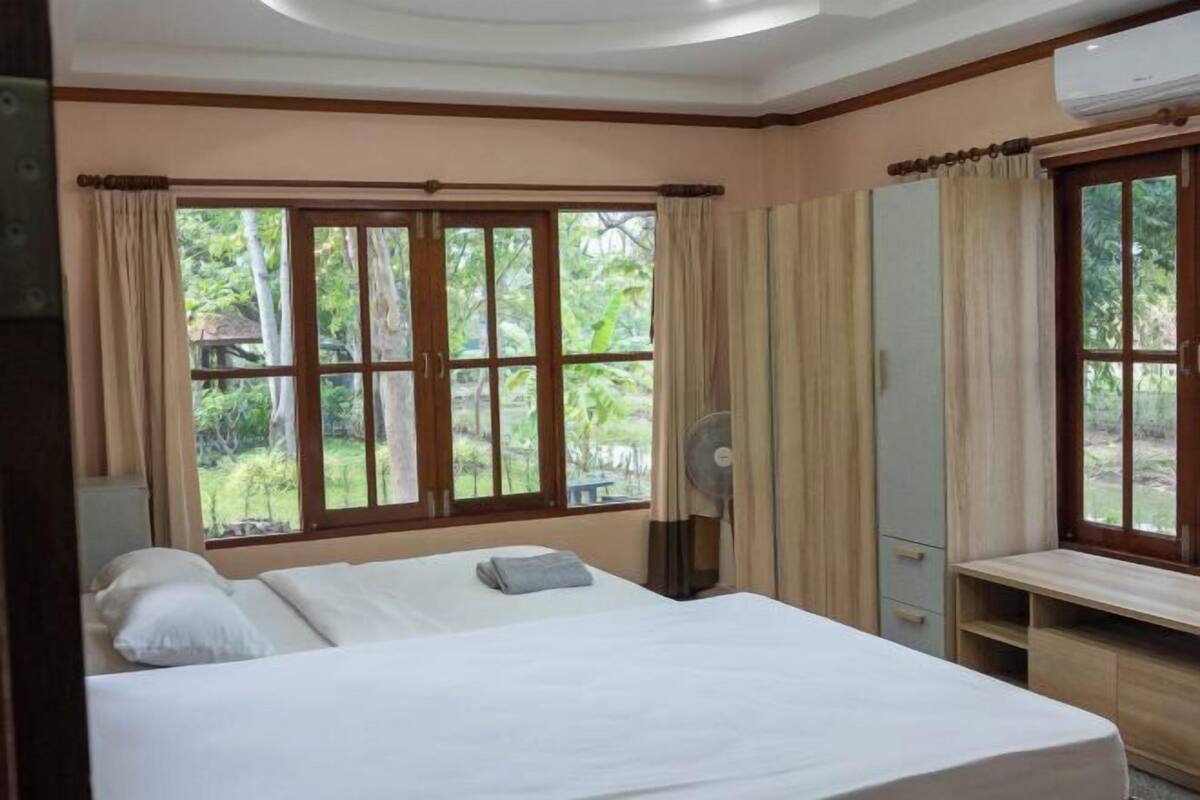 Un dormitorio con cama, escritorio, espejo y ventana con cortinas.