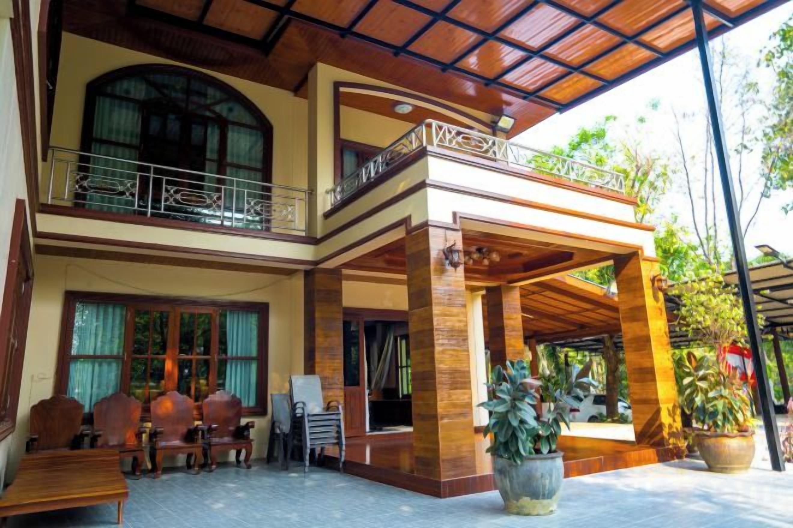 A two-story building with a covered outdoor area, wooden furniture, and potted plants.