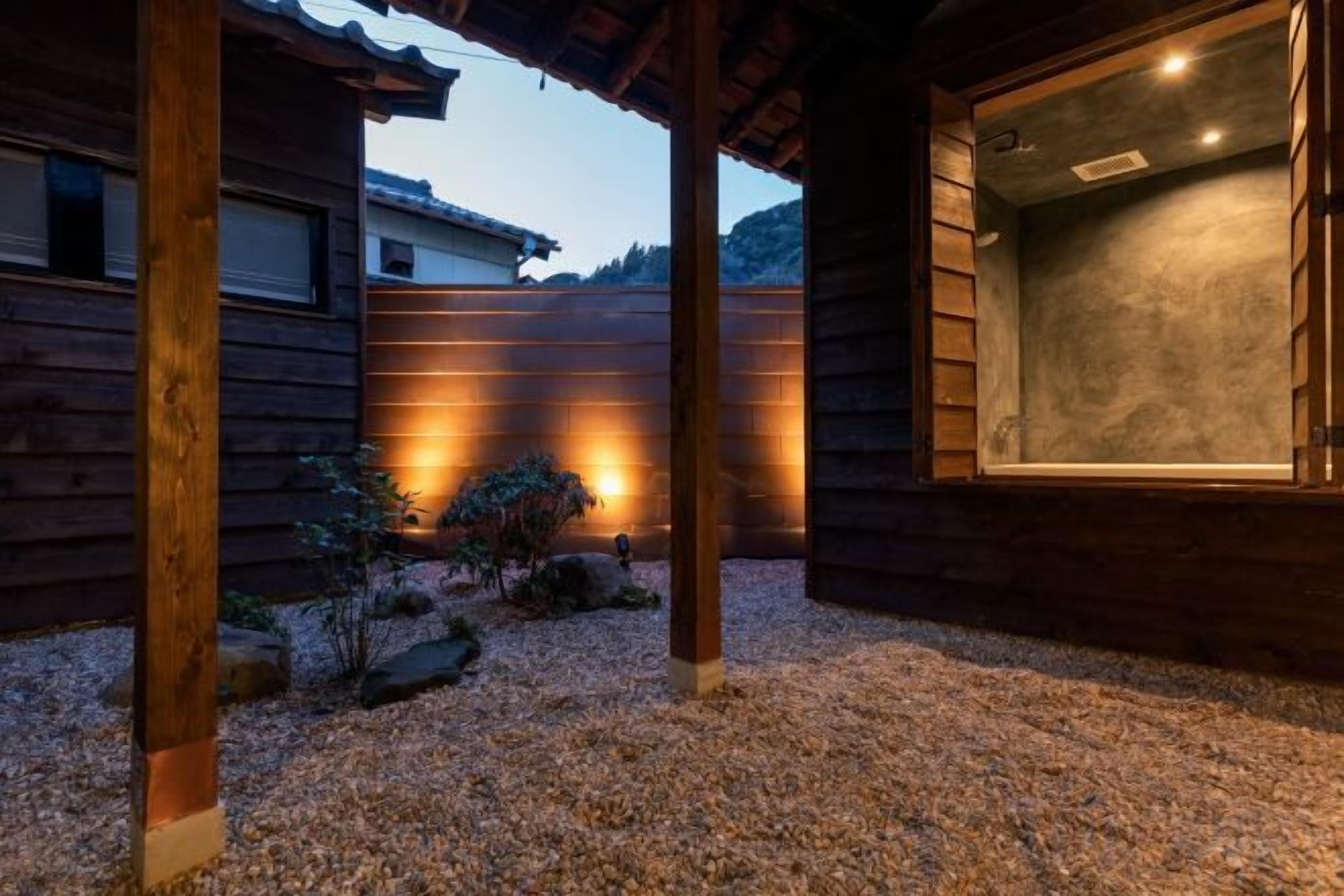 A wooden building with a large window and a covered outdoor area with gravel.