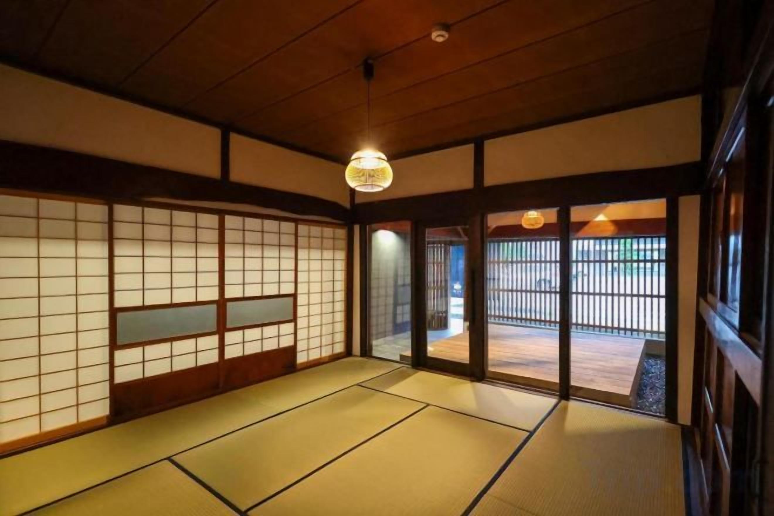 A traditional Japanese room with tatami flooring, sliding doors, and a hanging light fixture.