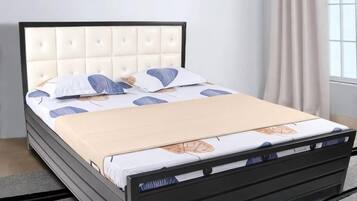 Un lit avec une tête de lit capitonnée, une literie blanche et un plaid beige.
