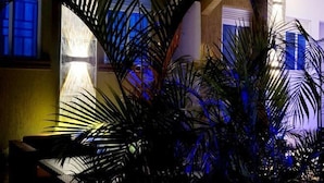 A room with a large window, a plant in the foreground, and a view of a building outside. - Erykah Hotel Mityana Road (Mawokota)