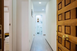 Un couloir menant à une pièce dont la porte est en bois.