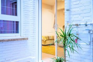 Une pièce avec un lit, une plante et un mur en briques blanches.