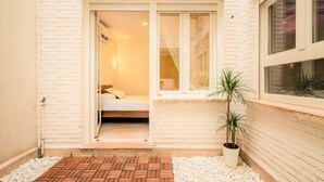 Een kleine, privé kamer met een bed, een raam en een plant in pot.