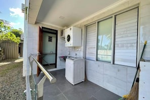 A laundry room with a washing machine, a dryer, and a window with blinds. - Affordable Apartment 3 Bedrooms (Suva)
