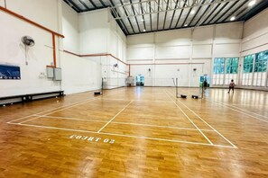 An indoor sports court with a wooden floor, marked lines, and a high ceiling.