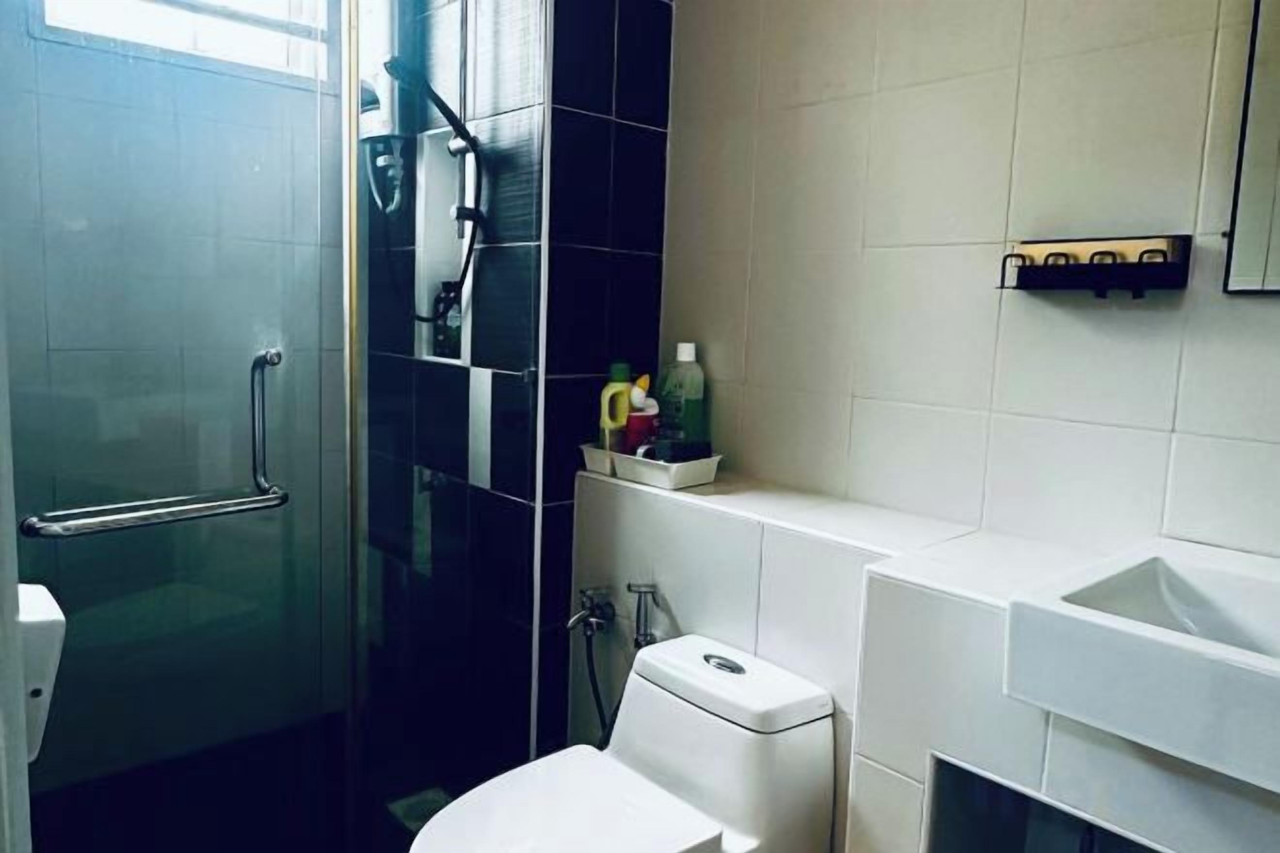Een badkamer met een douchecabine van glas, toilet en wastafel.
