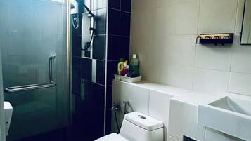 Een badkamer met een douchecabine van glas, toilet en wastafel.