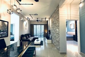 A modern living room with a sofa, coffee table, and a dining area with a marble table. - Johor Cozy Home 2 Rooms & Easy Parking Fast WiFi ! (Plentong)