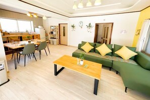 A living room with a green sofa, a wooden coffee table, and a dining area with chairs and a table. - Mintmint (Noboribetsu)