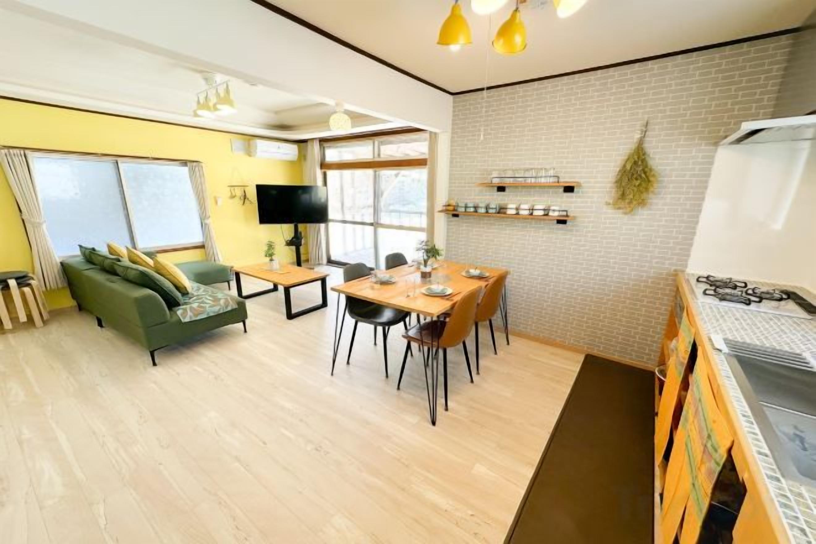 A compact living space with a dining area, a sofa, a TV, and a kitchenette.