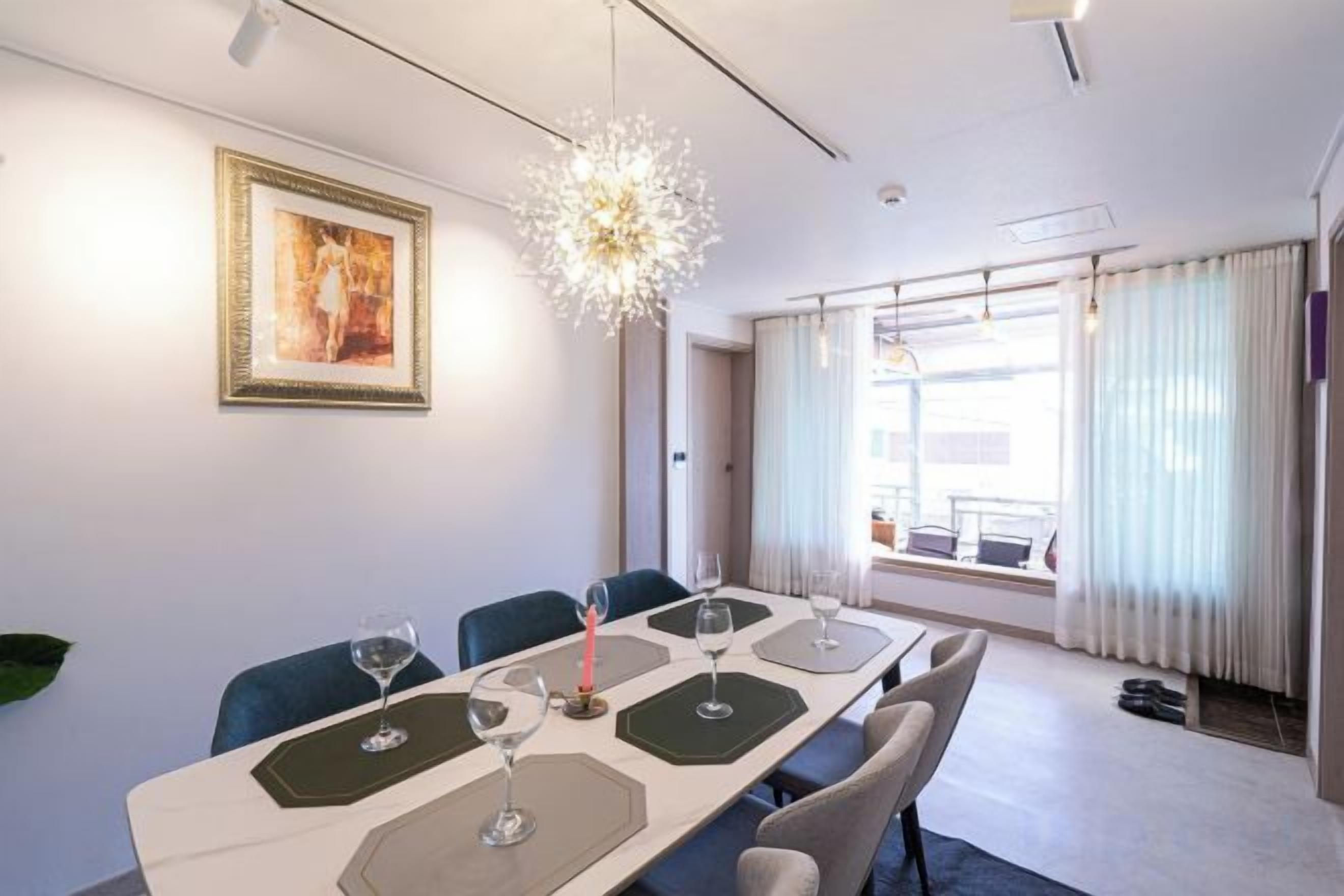 A hotel dining room with a long table, chairs, and a chandelier.