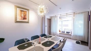A hotel dining room with a long table, chairs, and a chandelier.
