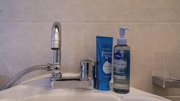 A bathroom sink with a faucet, a soap dispenser, and a bottle of liquid soap.