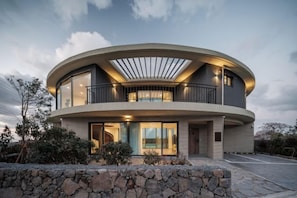 Un bâtiment moderne de forme circulaire, doté d’un balcon et de grandes fenêtres.