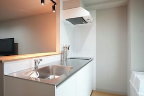A modern kitchen with a stainless steel sink, white cabinets, and a built-in oven. - Tasone Stay OSAKA STB4F (Osaka)