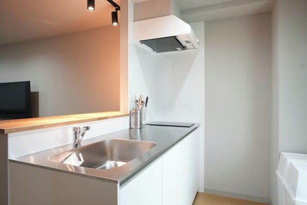 Una cocina moderna con un lavamanos de acero inoxidable, armarios blancos y un horno empotrado.