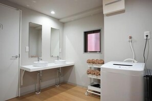 Casa de banho com duas pias, um espelho, um porta-toalhas e área de duche.