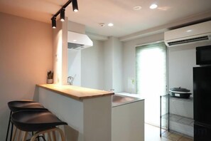 Cozinha compacta com bancada, pia e geladeira.