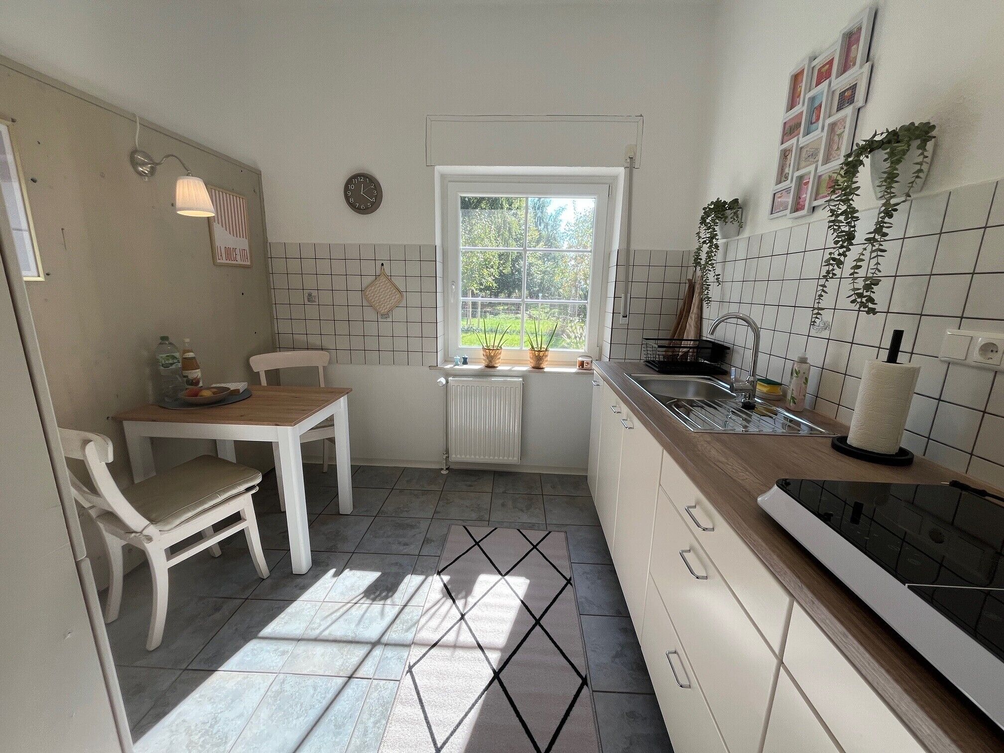A kitchen with a dining table, chairs, a window, a radiator, and a sink.