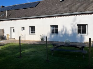 A white building with a tiled roof, multiple windows, a door, and a fenced yard with a picnic table. - Holiday Apartment at Conradhof 2 with Garden and Nature Views (Goch)
